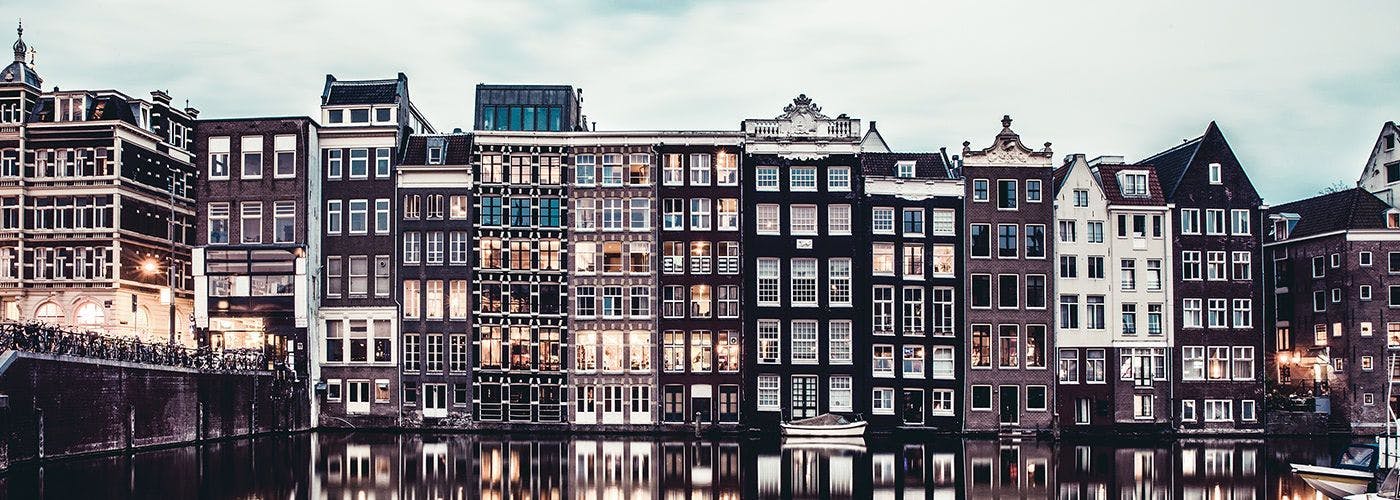 Amsterdam's canal houses at dusk reflecting on the water, epitomizing the serene Dutch environment suitable for VPS hosting services in the Netherlands.