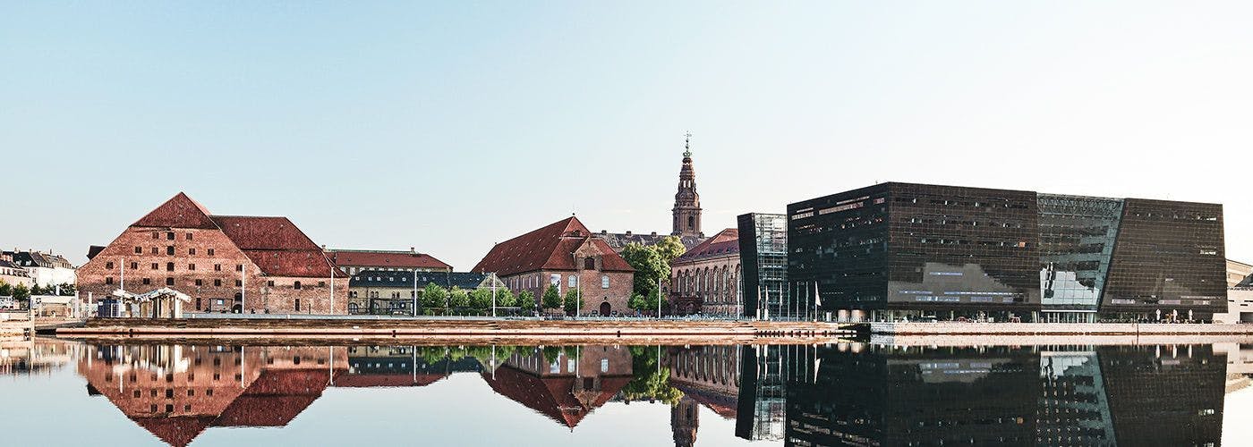 The historical and modern architecture of Copenhagen, Denmark, reflecting over water, symbolic of the city's innovative VPS hosting landscape