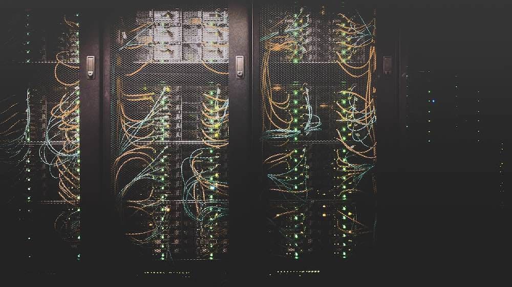 Server racks in a data center with numerous cables and glowing LED lights, illustrating the infrastructure of VPS hosting services.